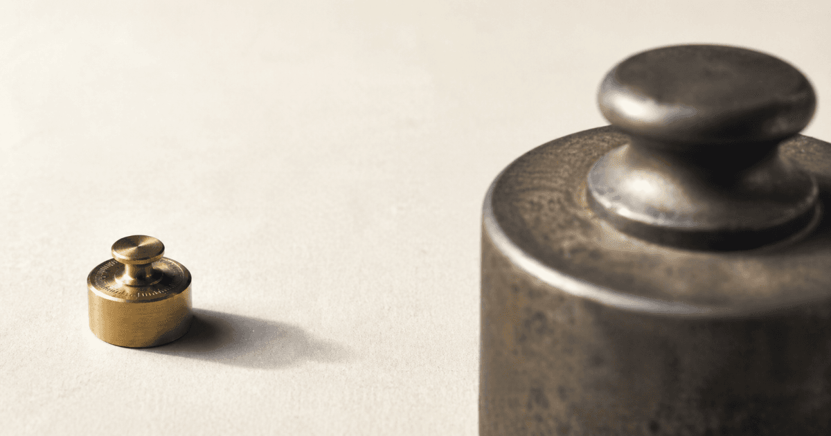 Small precision brass weight beside a much larger industrial steel weight, illustrating focus versus scale in venture capital
